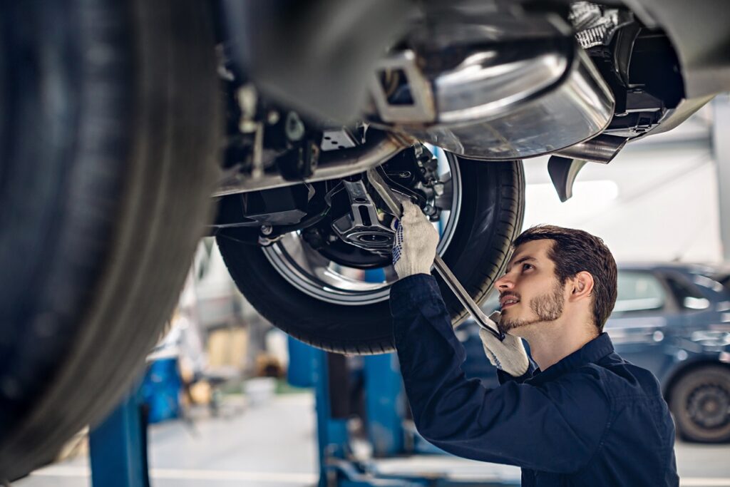 Mechaniker arbeitet an einem Fahrzeug, das auf einer Hebebühne steht.